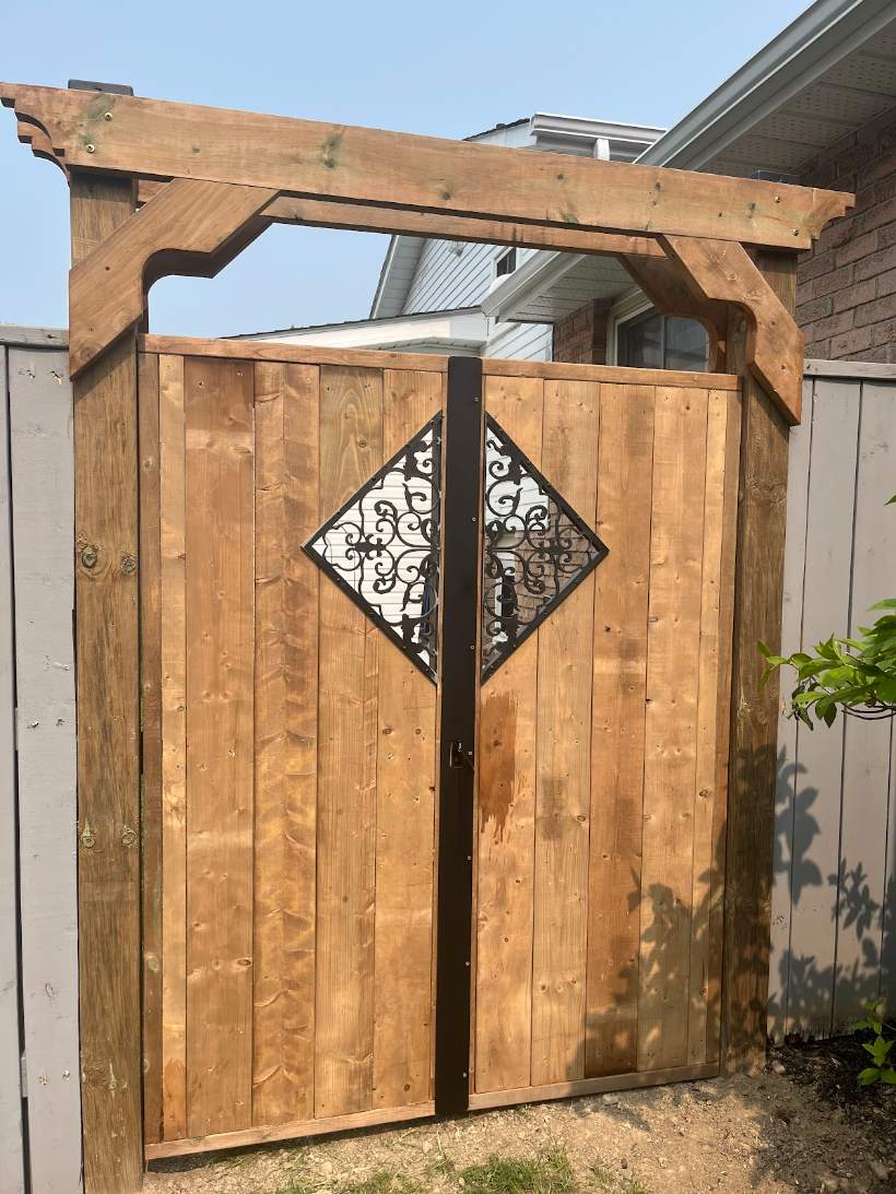 Custom arched cedar gate with decorative wrought-iron insert