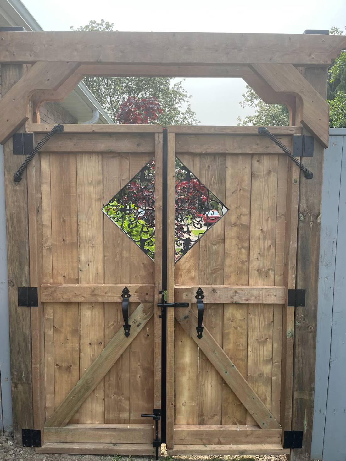 Custom arched cedar gate with decorative iron insert built by Outdoor Improvements in Hamilton